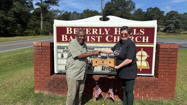 two people shake hands and receive a produce box