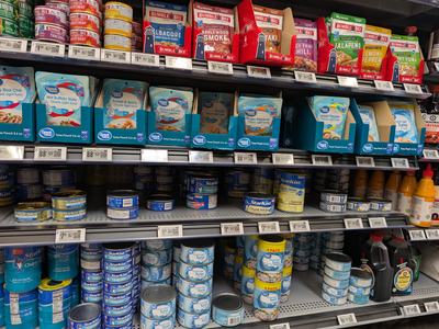Cans of tuna on shelf at grocery store.
