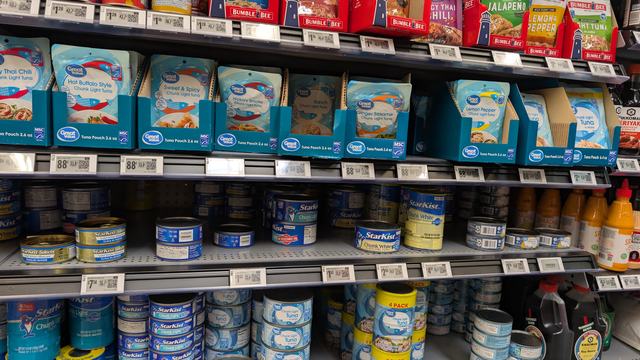 Cans of tuna on shelf at grocery store.