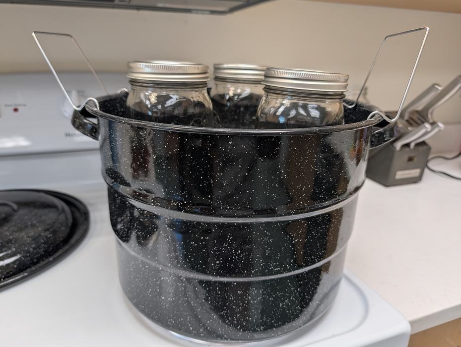 Pickles in canning device on stove.