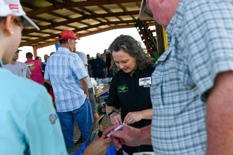 An Extension employee chats with people at an agriculture expo.