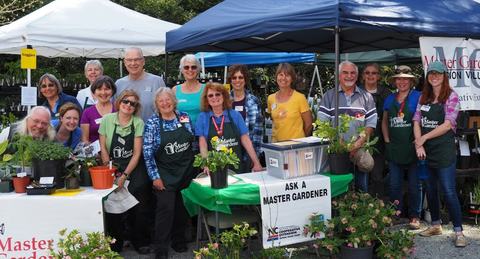 A group of Extension Master Gardener Volunteers pose with an Ask a Master Gardener stall.