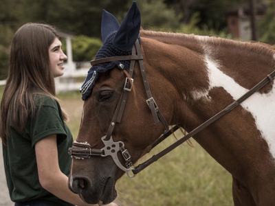 Young woman beside bridled chestnut-and-white horse outdoors