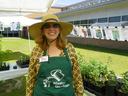 Woman wearing wide-brim hat and "Master Gardener" apron at outdoor plant sale booth