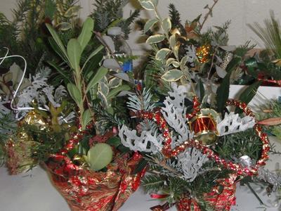 Two holiday floral arrangements with evergreen sprigs, variegated leaves, red garland and ornaments