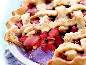 Lattice-top cherry pie with one slice removed in a ceramic pie dish