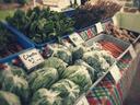picture of greens, cilantro and carrots at a farmers market stand