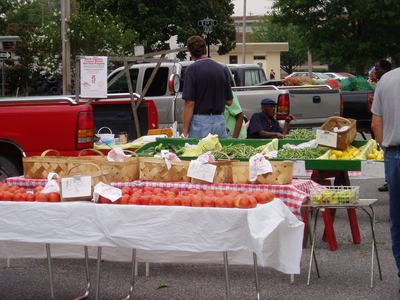 Farmers market table with baskets of tomatoes and sign "$1.50 lb".