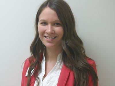 Woman with long brown hair wearing white blouse and red blazer, smiling