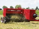 Red Case IH SB541 hay baler picking up cut hay in a field