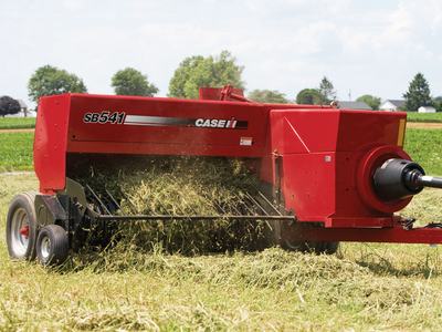 Red Case IH SB541 hay baler picking up cut hay in a field