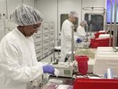 Two technicians in cleanroom suits working at a sterile lab bench; box labeled "500".