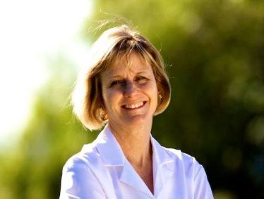 Woman with short blond hair wearing a white collared shirt standing outdoors