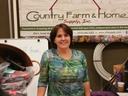 Woman standing at a booth with "Country Farm & Home Supply, Inc." banner behind her