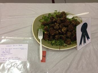 Plate of meatballs on lettuce with a plastic fork, blue ribbon award and handwritten note