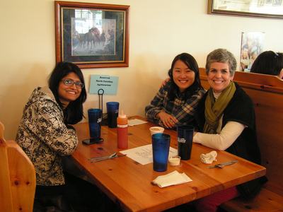 Three people seated at a wooden restaurant table with sign "Reserved North Carolina Agritourism"