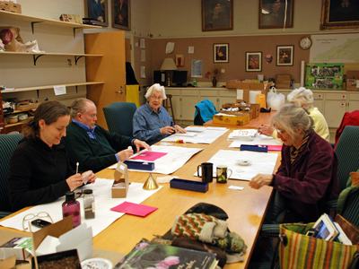 People seated around a long table working on crafts in a community room