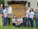 Seven people posing at wooden sign reading "Jackson's Mill State 4-H Camp" and "Stonewall Jackson Jubilee"