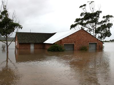 Brick building partially submerged in floodwater with trees around