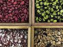 Four wooden bins holding four varieties of dried beans: red, green-black, maroon-white, tan-speckled