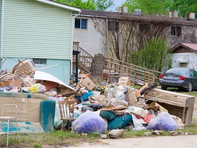 Household debris and furniture piled outside a multiunit building near a parked car