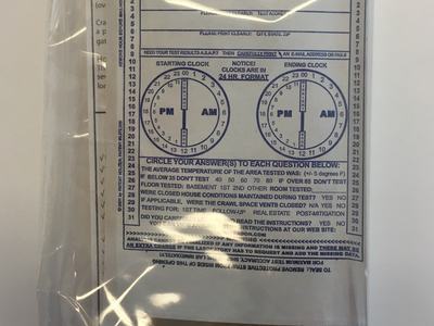 Sealed radon test kit with printed form showing start and end clock dials and ID 8305367