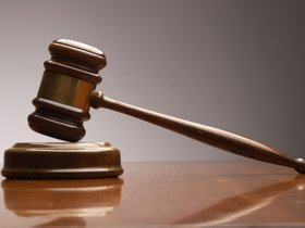 Judge's gavel resting on wooden sound block on polished surface