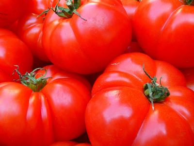 Red tomatoes with green stems clustered together