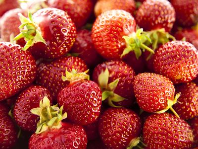 Close-up of multiple ripe red strawberries with green calyxes and seeds visible