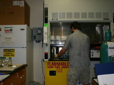 Person working at a lab fume hood labeled "Flammable Keep Fire Away"