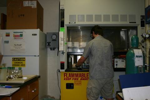 Person working at a lab fume hood labeled "Flammable Keep Fire Away"
