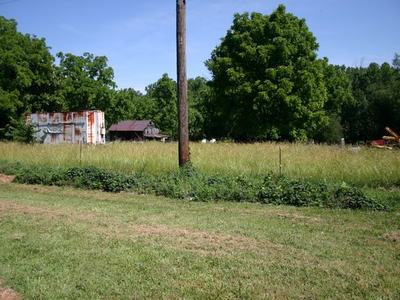 Rusty shipping container and small barn behind tall grass with utility pole in foreground
