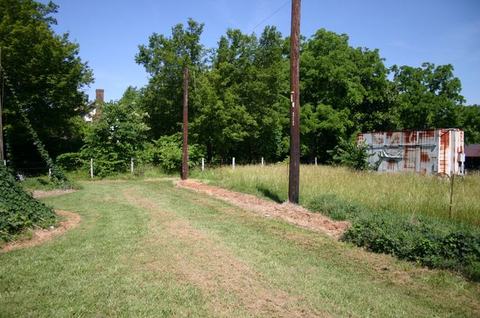 Mowed grassy track with utility poles leading to trees and a rusted shipping container