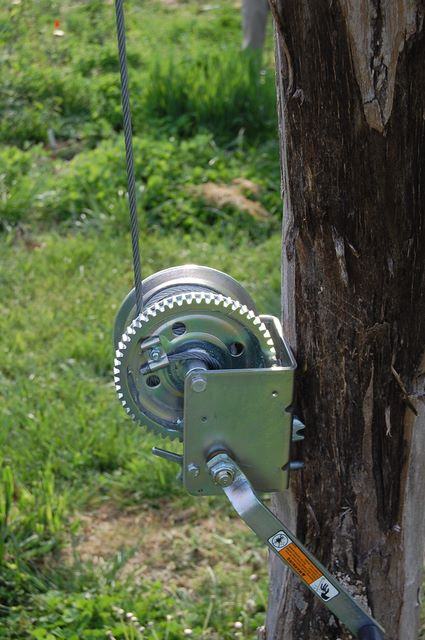 Hand crank winch mounted on a wooden post with steel cable attached