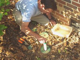 Inserting a tube of termite bait into a bait station.