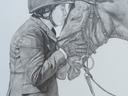 Equestrian in helmet and jacket kissing and holding bridled horse's muzzle