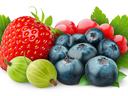 Strawberry, blueberries, red currants and gooseberries arranged on green leaves