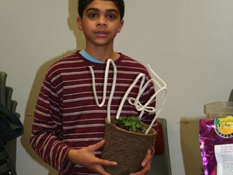Young person holding a potted plant with white wire supports indoors