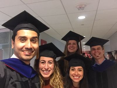 Group of graduates wearing caps and gowns standing in a hallway