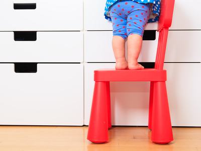 kids safety concept- little girl climbing on baby chair