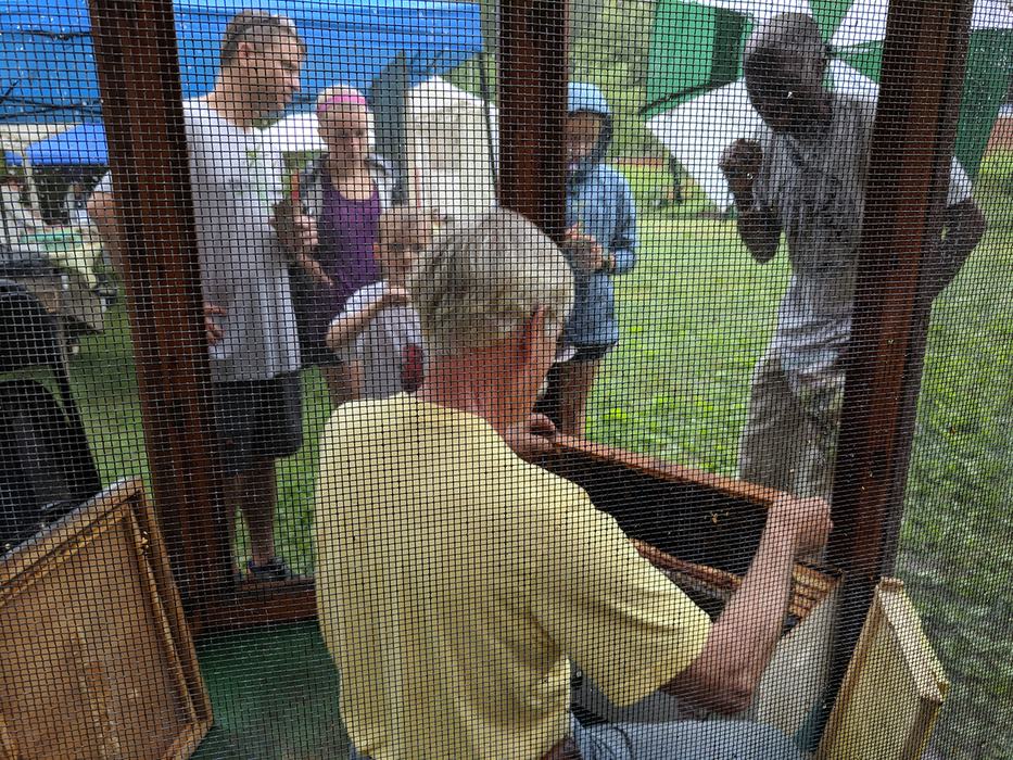 Apiary Inspector Supervisor Don Hopkins does a beekeeping demo in the bee cage. 
