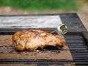 Grilled chicken half with a themometer on a grill