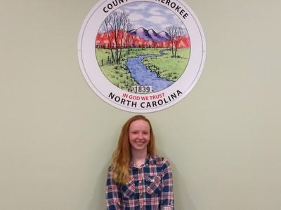 Person standing beneath Cherokee County seal and the text "IN GOD WE TRUST"