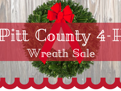 Evergreen wreath with red bow and banner reading Pitt County 4-H Wreath Sale