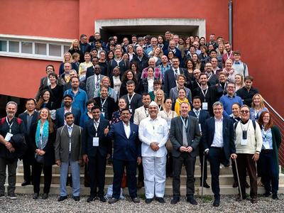 Large group of conference attendees posing for a group photo on outdoor stairs