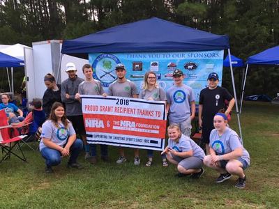 Group holding banner reading 2018 PROUD GRANT RECIPIENT – NRA & NRA FOUNDATION