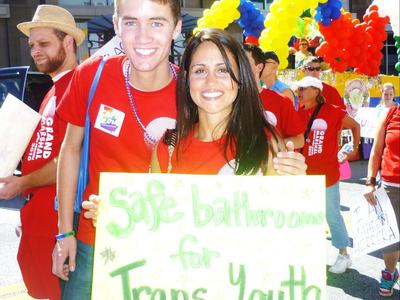 Austin and Maru holding a sign that read, "Safe bathrooms for trans youth"