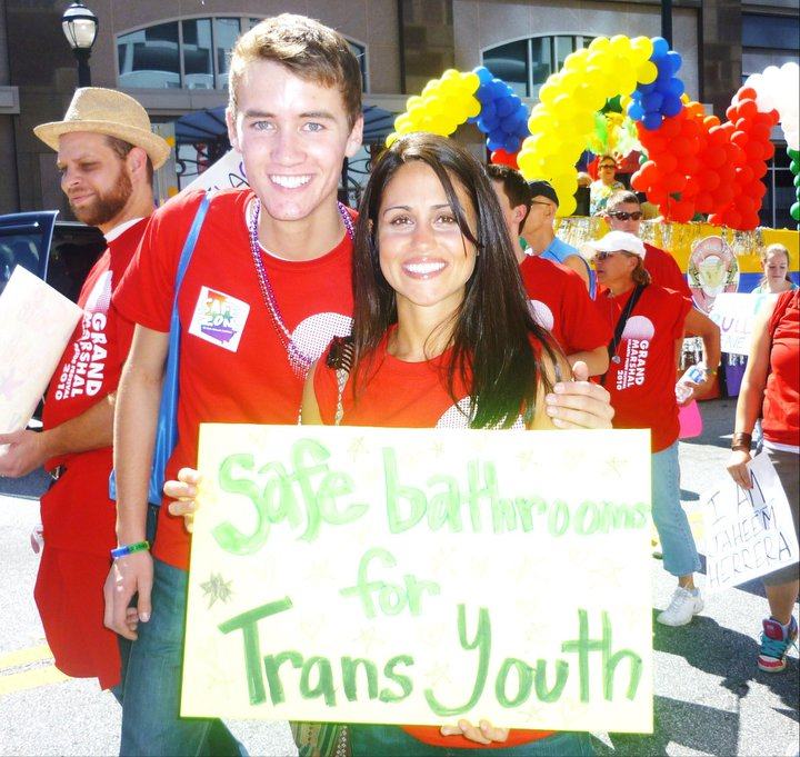Austin and Maru holding a sign that read, "Safe bathrooms for trans youth"
