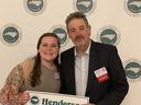 Two people holding a sign reading "Henderson" in front of North Carolina Association logos