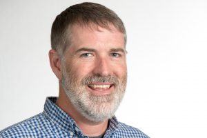 A headshot of a man smiling.
